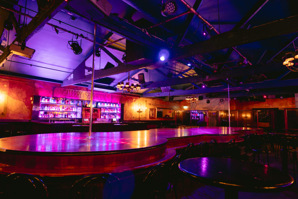 The Men's Gallery main stage and bar under purple lighting